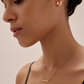 Gold horizontal bar pendant necklace on model with huggies